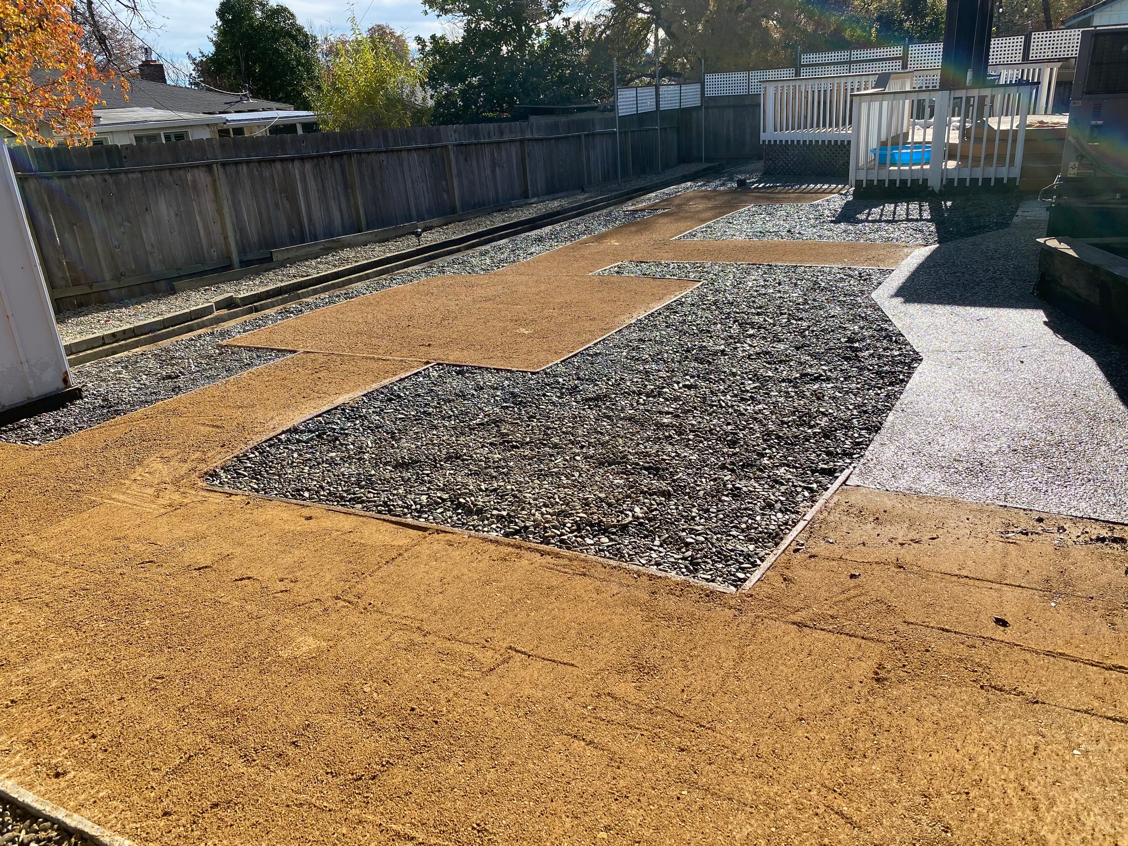 Geometric backyard landscaping with sections of tan decomposed granite and grey gravel.